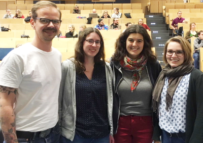 Gruppenbild mit vier Personen in einem Hörsaal der Uni Rostock. Die Sitzreihen im Hintergrund. (Foto: ArbeiterKind.de)